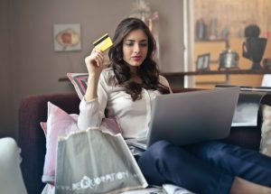 Michigan Debt Reduction woman holding card while operating silver laptop 919436 300x215 1